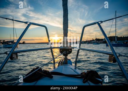 Yacht amarré sur des bouées près du rivage dans la baie d'Uvala Gradina près de la ville de Vela Luka sur l'île de Korcula aux lumières du coucher du soleil en Croatie Banque D'Images