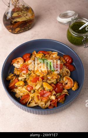 Nouilles aux crevettes, moules, tomates, oignons et câpres. Les pâtes sont servies avec de l'huile d'olive et de la sauce pesto. Cuisine méditerranéenne traditionnelle maison Banque D'Images