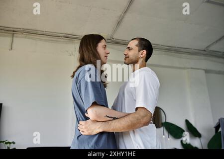 Un jeune couple gay s'embrasse dans une chambre, exprimant leur amour l'un pour l'autre. Banque D'Images