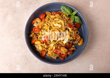Nouilles aux crevettes, moules, tomates, oignons et câpres. Les pâtes sont servies avec de l'huile d'olive et de la sauce pesto. Cuisine méditerranéenne traditionnelle maison Banque D'Images