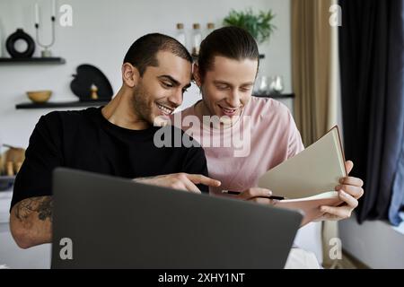 Un jeune couple gay partage un moment tendre en lisant un livre dans leur maison moderne. Banque D'Images