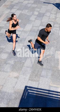 Vue d'en haut de jeune couple en équipement de sport, axé sur l'entraînement dans la chaude journée d'été le matin. Coureurs athlètes en vêtements de fitness. Banque D'Images