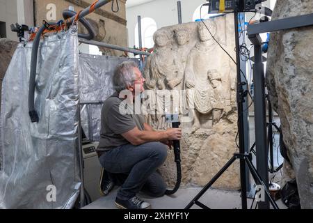 Mainz, Allemagne. 16 juillet 2024. Le restaurateur Mathias Steyer travaille sur la pierre dite de Blussus, une pierre tombale de l'époque romaine. La pierre tombale d'un Celte, qui est représentée avec sa femme Menimane sur un côté de la pierre et montre une inscription et la représentation d'un navire du Ier siècle sur l'autre côté, a été trouvée à Mayence-Weisenau. Crédit : Helmut Fricke/dpa/Alamy Live News Banque D'Images