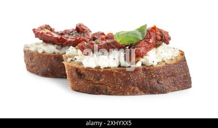 Délicieuse ricotta bruschettas avec tomates séchées au soleil et basilic isolé sur blanc Banque D'Images