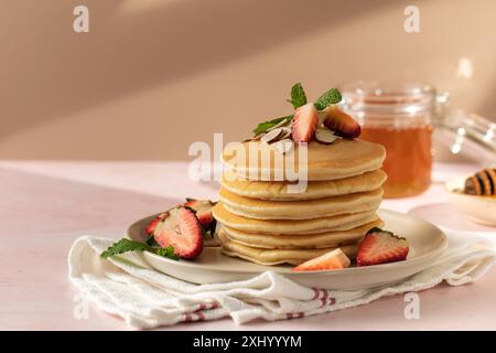 Profitez d'un merveilleux petit déjeuner avec des crêpes, des fraises et du miel sous la lumière chaude du soleil Banque D'Images