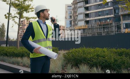 Entrepreneur caucasien ingénieur civil travailleur d'entretien électrique tenant le plan directeur masculin regardant l'homme de construction de bâtiment de ville Banque D'Images