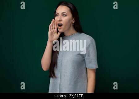 Une femme se tient debout devant un mur vert vif, sa posture est forte et bien fixée. Le mur sert de toile de fond vibrante à sa présence, CREA Banque D'Images