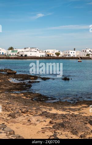 Eau calme de l'océan Atlantique et une architecture blanche typique. Montagne en arrière-plan. Ciel bleu avec des nuages blancs en hiver. Caleta del Sebo, Banque D'Images