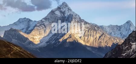 Montagne AMA Dablam au coucher du soleil et ciel bleu. Le soleil illumine les pentes. Montagnes de l'Himalaya, Népal. Banque D'Images