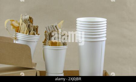 Tasse à café en papier blanc, papier usagé et boîte en carton sur une surface brune, en attente de recyclage. Encourage le recyclage des déchets, sauver la Terre et conserver Banque D'Images