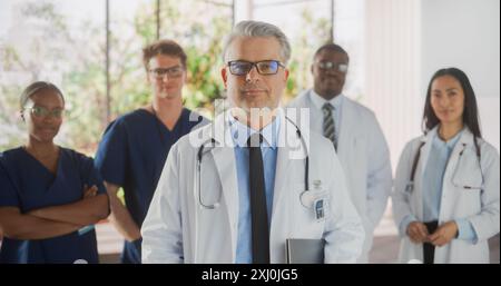 Groupe d'équipe multiethnique réussie de femmes et hommes médecins, infirmières et professionnels de la santé posant pour caméra et souriant. Portrait d'un médecin d'âge moyen confiant, premier dans la file Banque D'Images