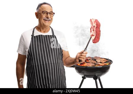 Homme mûr griller de la viande sur un barbecue et tenant un steak d'aloyau isolé sur fond blanc Banque D'Images