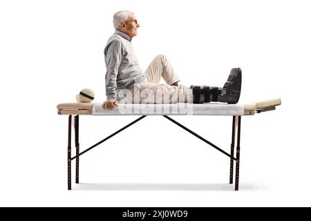 Homme âgé avec attelle orthopédique du pied assis isolé sur fond blanc Banque D'Images