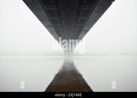 Sous le pont dans le brouillard. Pont sur une rivière - vue symétrique d'en bas. Pont disparaissant dans un brouillard dense. Banque D'Images