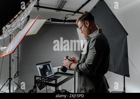 Un photographe professionnel examine des prises de vue dans un studio moderne Banque D'Images