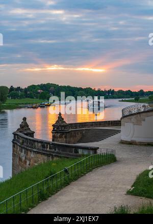 Coucher de soleil sur l'Elbe dans la célèbre ville de Dresde. Touriste, bateaux de plaisance naviguent lentement le long de la rivière au coucher du soleil devant un bel escalier en th Banque D'Images