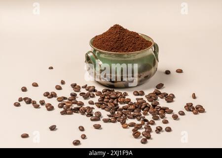 Une tasse verte avec du café moulu beaucoup de grains de café sur un fond blanc sont une boisson revigorante. Vigueur pour toute la journée. Café du matin. Arôme. Banque D'Images