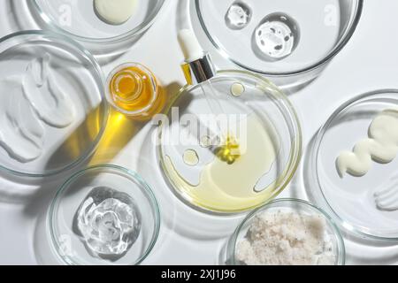 Boîtes de Petri avec différents produits cosmétiques sur fond blanc, pose à plat Banque D'Images