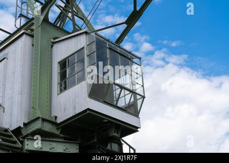 Gros plan de la cabine d'une grue portuaire avec de grandes fenêtres, sur fond d'un ciel bleu avec des nuages blancs. Banque D'Images