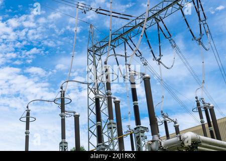 Une grande station de transmission d'énergie électrique avec de nombreuses tours et fils contre un ciel bleu brillant avec des nuages dispersés. Banque D'Images