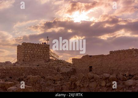 Les touristes marchant parmi le mur de la réserve nationale de Masada, une forteresse israélienne historique, pendant le coucher de soleil pittoresque dans le désert, Israël. Banque D'Images