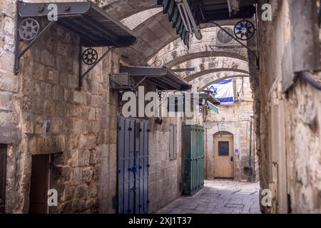 L'étroite route de Bab El-Hadid dans la vieille ville de Jérusalem, avec le drapeau israélien, et panneau de direction vers le mur occidental et le Mont du Temple. Banque D'Images