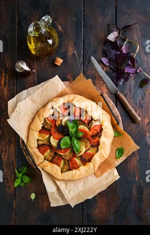 Galette ratatouille aux aubergines, courgettes, tomates. Plat traditionnel français fait maison avec des ingrédients et des ustensiles de cuisine sur une vieille table en bois backgr Banque D'Images