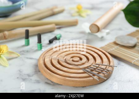 Dessous de verre en bois avec aiguilles d'acupuncture sur table en marbre blanc Banque D'Images