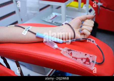 Prélever du sang sur le vain d'un donneur. Bras sur accoudoir, aiguille hypodermique, tubes, récipient avec sang. Le stati de transfusion sanguine de la ville (municipale) Banque D'Images