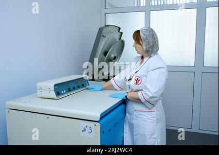 Infirmière touchant l'interrupteur de la centrifugeuse pour commencer le processus de séparation du sang. La station de transfusion sanguine de la ville (municipale). 5 avril 2019. Kiev, Royaume-Uni Banque D'Images