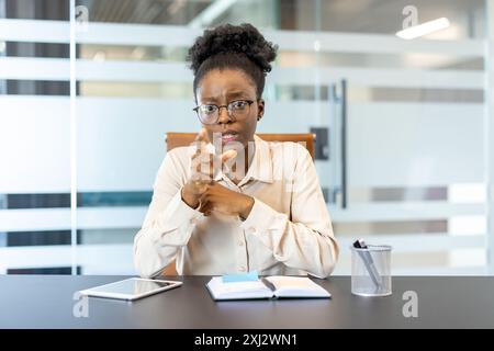 Femme d'affaires ayant une réunion en ligne dans un bureau moderne, discutant du travail et pointant vers la caméra. Professionnel confiant engagé dans une conférence téléphonique virtuelle, dirigeant la conversation à distance Banque D'Images