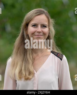 Neuenhagen BEI Berlin, Allemagne. 16 juillet 2024. Jessica Görß, propriétaire de la pépinière 'Wildblüten', se tient derrière les feuilles vertes des plantes vertes. Le ministère de l'environnement du Brandebourg et la Société allemande d'horticulture (DGG) ont nommé la verruelle commune (Achillea millefolium) « plante sauvage de l'État du Brandebourg » à la pépinière. Dans le même temps, l'entreprise horticole fondée par Jessica Görß en 2019 a été honorée comme première pépinière de plantes sauvages de Brandebourg de l'année. Crédit : Soeren Stache/dpa/Alamy Live News Banque D'Images