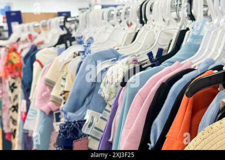 un porte-vêtements rempli de divers vêtements colorés sur cintres dans un cadre de magasin de détail Banque D'Images