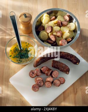 Ajoutez les saucisses tranchées aux pommes de terre (recette vidéo : Salade d'hiver) Banque D'Images