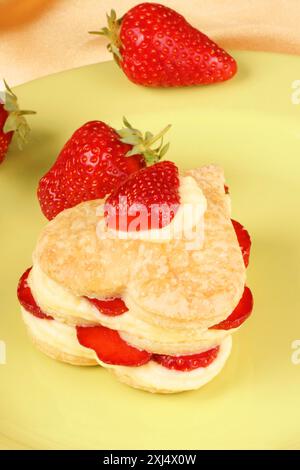 Fraises en forme de coeur et millefeuille de crème anglaise sur une assiette verte. Pour une douce Saint Valentin. Mise au point sélective Banque D'Images