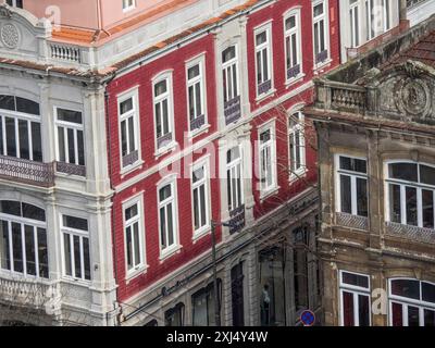 Façade de maison rouge dans le centre historique avec de nombreuses fenêtres et balcons, à côté d'un ancien bâtiment en besoin de rénovation, Porto, Douro, Portugal Banque D'Images