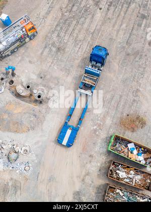 Gros plan d'un camion et de conteneurs avec des gravats de construction sur un chantier de construction, site de démolition d'une ancienne entreprise de transport de camions avec des réservoirs d'huile Banque D'Images