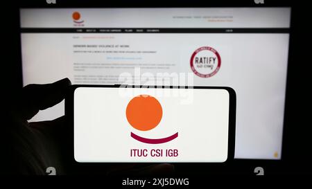 Stuttgart, Allemagne, 02-13-2024 : personne tenant un smartphone avec le logo de la Fédération Confédération syndicale internationale (CSI) devant le site web. Banque D'Images