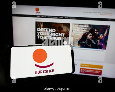 Stuttgart, Allemagne, 02-13-2024 : personne tenant un téléphone portable avec le logo de la Fédération Confédération syndicale internationale (CSI) devant la page web. Banque D'Images