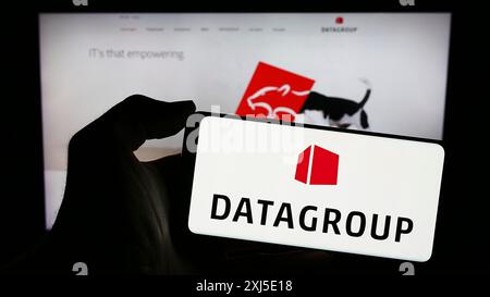 Stuttgart, Allemagne, 02-13-2024 : personne tenant un téléphone portable avec le logo de la société allemande de technologie de l'information DATAGROUP se devant l'entreprise Banque D'Images