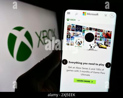 Stuttgart, Allemagne, 02-14-2024 : personne tenant un smartphone avec le site de la console de jeux vidéo Xbox (Microsoft) devant le logo de l'entreprise. Concentrez-vous sur Banque D'Images