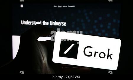 Stuttgart, Allemagne, 02-19-2024 : personne tenant un téléphone portable avec le logo du chatbot d'intelligence artificielle générative Grok (X.. AI) devant la page Web. Banque D'Images