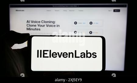 Stuttgart, Allemagne, 02-19-2024 : personne tenant un téléphone portable avec le logo de la société américaine d'intelligence artificielle ElevenLabs Inc devant l'entreprise Banque D'Images
