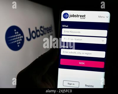 Stuttgart, Allemagne, 02-22-2024 : personne tenant un smartphone avec la page web de la société de plate-forme d'emploi Jobstreet devant le logo de l'entreprise. Concentrez-vous sur Banque D'Images