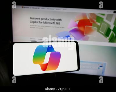 Stuttgart, Allemagne, 02-22-2024 : personne tenant un téléphone portable avec le logo du chatbot d'intelligence artificielle Microsoft CoPilot devant la page Web de l'entreprise. Banque D'Images