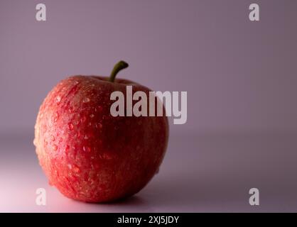 Pomme rouge fraîche avec des gouttelettes d'eau sur un fond blanc Banque D'Images