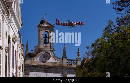 Condor avion de vacances, avion, vole bas au-dessus de l'arche de la ville, nids de cigognes, nid, cigognes nichant sur l'arche, Arco da Vila, vieille ville, Faro, Algarve Banque D'Images