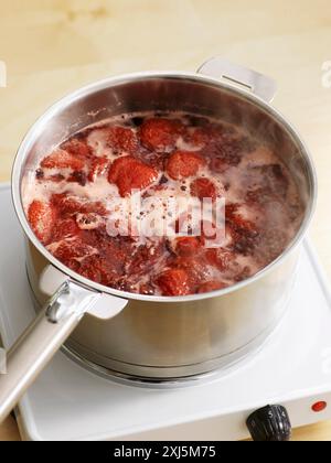 Mettre les fraises, le sucre et le jus de citron dans une casserole et faire bouillir Banque D'Images