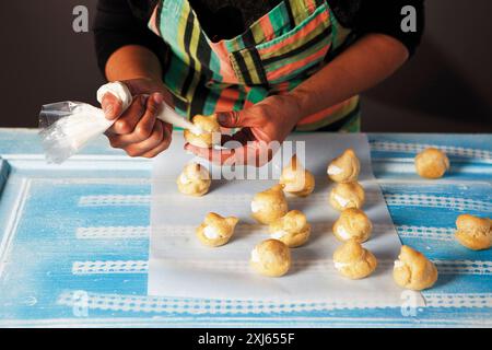 Après la cuisson, remplissez les pâtisseries feuilletées de crème à l'aide d'un sac à passepoil Banque D'Images