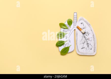 Poumons en papier avec cigarette et feuilles vertes sur fond jaune Banque D'Images